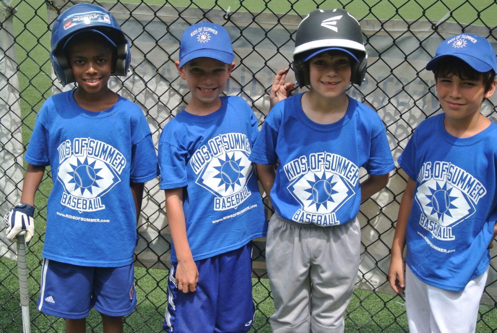 Four teammates smiling by chain-link fence