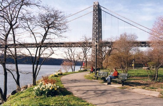 Riverside path with benches and suspension bridge