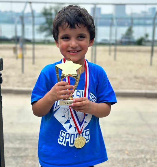 Smiling boy holding trophy and medal